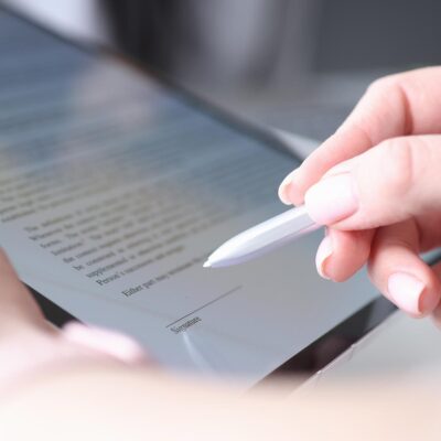 Woman hand holds stylus and puts an electronic signature in contract on tablet